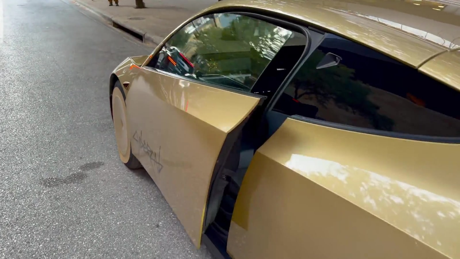 Vista lateral de un Tesla Cybercab dorado con sus puertas abiertas